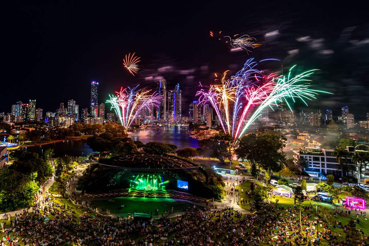 Gold Coast events fireworks bursting over the city skyline as crowds gather in a riverside park for a live outdoor celebration at night