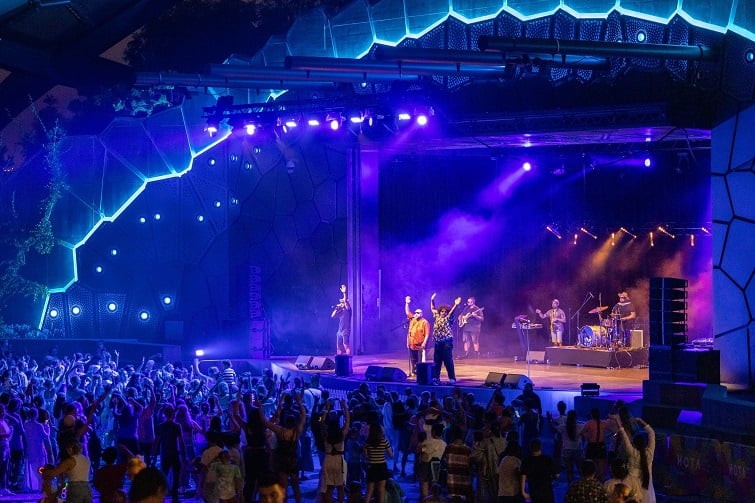 Crowd cheering at an outdoor stage with live band, coloured lights and smoke effects during a night show, a standout for entertainment in gold coast