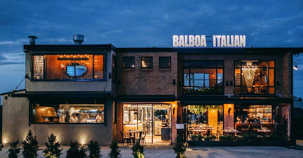 arrival-night-dinners-near-royal-palm Balboa Italian restaurant lit up at dusk, a short walk from Royal Palm for arrival-night dinner near Palm Beach